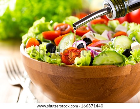 oil pouring into bowl of salad