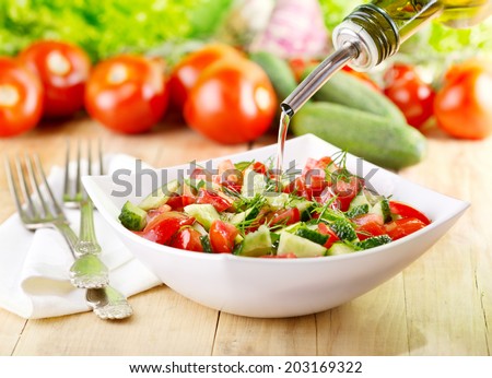 olive oil pouring  into bowl of vegetable salad