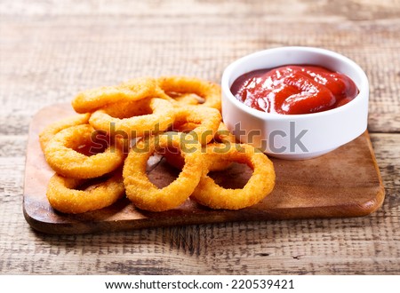 onion rings with ketchup on wooden board