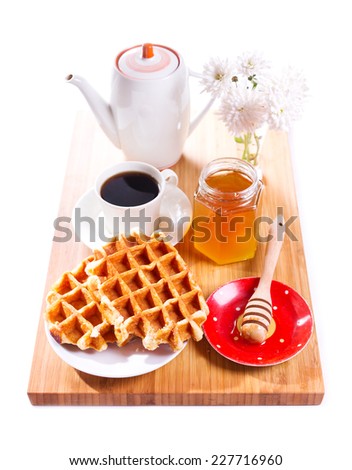 breakfast with waffles, honey and coffee on wooden board on white background