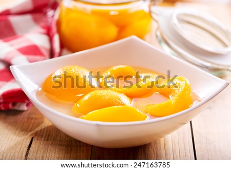 canned peaches in a bowl on wooden table
