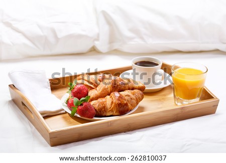 breakfast in bed with coffee, croissants, strawberries and juice