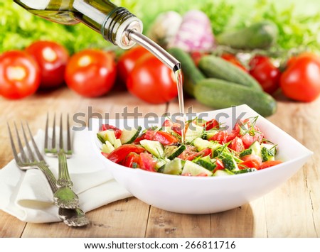 oil pouring  into bowl of vegetable salad