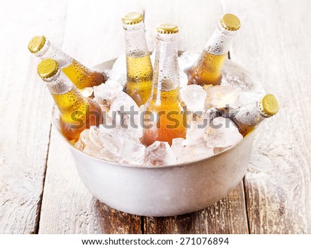 cold bottles of beer in bucket with ice on wooden table