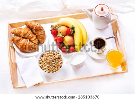 Breakfast in bed. Tray with coffee, croissants, cereals and fruits