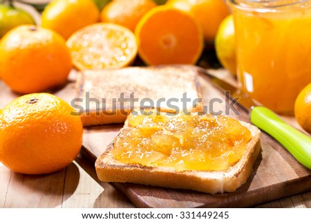 toast with orange mandarin marmalade with fresh fruits on wooden table