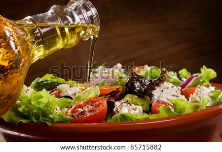vegetable salad with olive oil pouring from a bottle