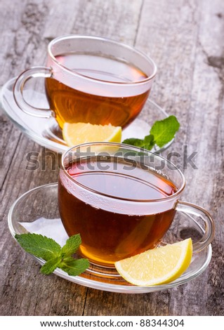 cups of tea with mint and lemon on wooden table