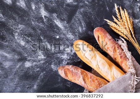 bread with wheat ears on dark board with flour, top view