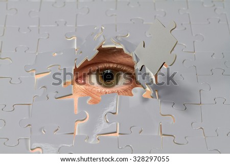An eye looking out from a hole in a puzzle.