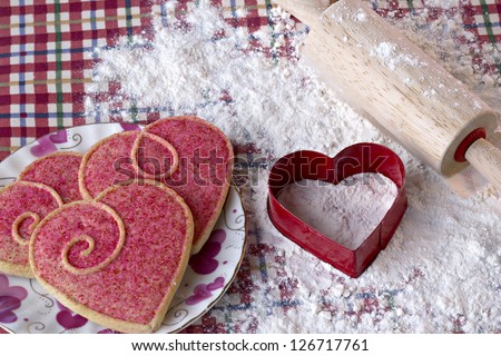 Beautiful heart shaped cookies, cutter and rolling pin in flour on red checked cloth