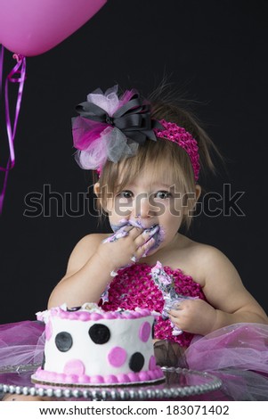 Beautiful little one year old girl messy with birthday cake