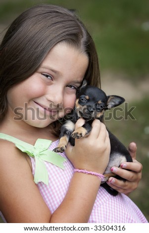 Beautiful little seven-year-old girl with missing teeth smiling while he cuddles a cute little puppy