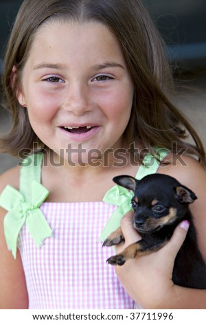 Beautiful little seven-year-old girl with missing teeth smiling while she cuddles a cute little puppy