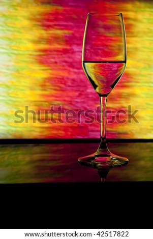 Wine glass in front of lighted background showing colors of pink, yellow and green