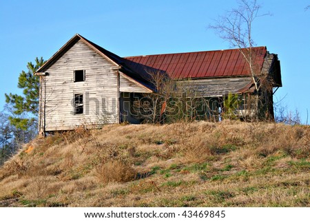 Abandoned old wooden house in the country with rusted tin roof and blue sky