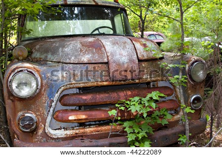 stock photo Junk yard vehicles showing old rusted truck in overgrown weedy 