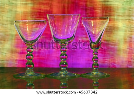 Three beautiful wine glasses with pink, red and yellow lighted background