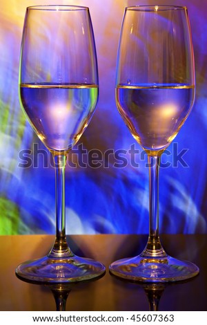 Two beautiful wine glasses with orange, blue, yellow, green and red lighted background