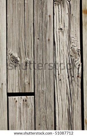 Rustic old weathered wall or fence with knotholes, nail heads and rust showing on vertical planks