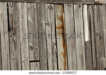 Rustic old weathered wall or fence with knotholes, nail heads and rust showing on vertical planks