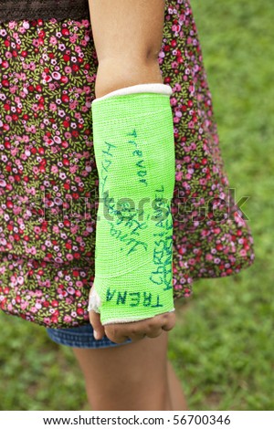 Little girl\'s arm wearing a neon green cast that has been autographed by friends
