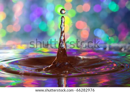 Colorful red, yellow, pink green and blue water drop and splash with reflections of colorful background in drop