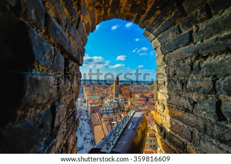 Views from Garisenda tower in Bologna, Italy throug a window to he city center with a surveillance camera in the foreground and the bricks of the tower as the natural frame