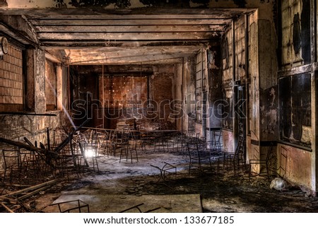 interior of an abandoned building with old chairs, lit by a ray of light - desolate and sad hall with the windows bricked