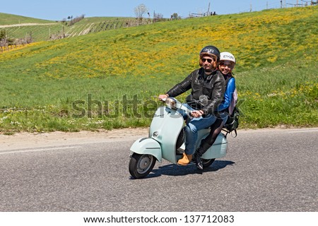 Imola (Bo) Italy - April 14: An Happy Couple Riding A Vintage Scooter Vespa In The Italian Countryside During The Scooters Rally &Quot;Iv Vespa In Fiore&Quot; On April 14, 2013 In Imola (Bo) Italy