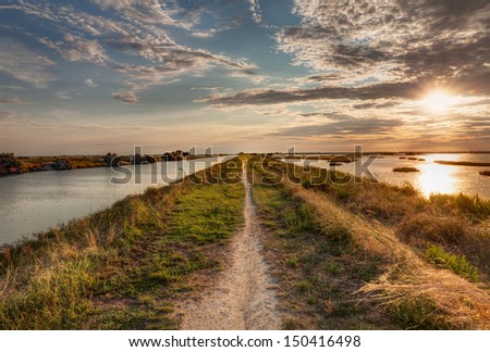 panorama at sunset of the wetland, a long straight path across the lagoon in the natural reserve \