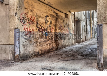 narrow alley in the old town - corner of a decadent city street and grunge wall with graffiti - draw of smoker of hashish - drug addiction, marijuana, cannabis, joint, reefer, spliff