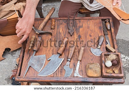 work table with old tools of the artisan shoemaker for cutting and sewing the leather - reenactment of ancient medieval work
