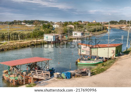 landscape of the wetland in Comacchio, Ferrara, Italy - fishing huts with net on the canal of the lagoon