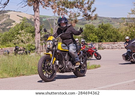 PREDAPPIO, ITALY - MAY 10: biker riding italian motorbike Ducati Scrambler with a group of bikers in motorcycle rally \