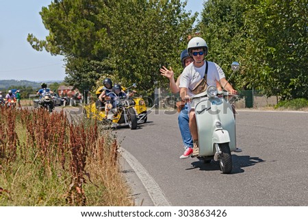 PIEVEQUINTA, FORLI\', ITALY - JULY 19: couple riding vintage scooter Vespa with a group of bikers during the motorcycle rally \