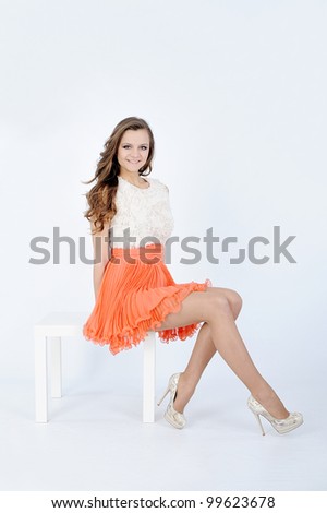 beautiful young female with orange skirt in white background