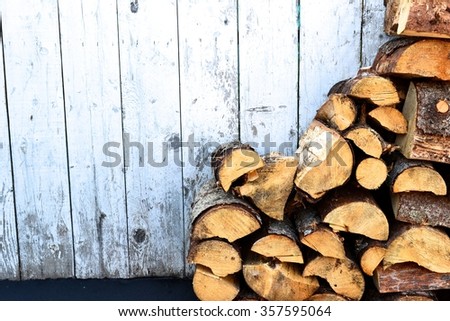 Chopped firewood stacked next to a white picket fence at a fish camp in Alaska.