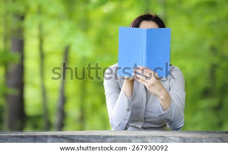 Woman holding book in front of her face