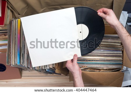 Retro styled image of a collection of old vinyl record lp\'s with sleeves on a wooden background. Browsing through vinyl records collection. Music background. Copy space.