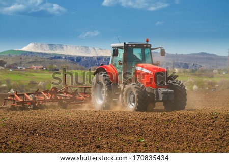 Brand new red tractor on the field working on land