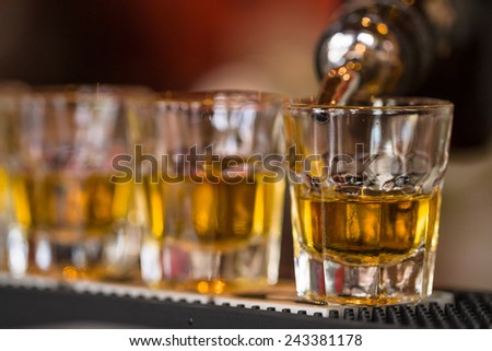 Barman makes whisky shot drinks in row. Alcoholic shots in nightclub