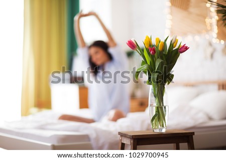 Girl with flowers tulips sits on a bed. She has just woken up and have presented her a bouquet of flowers