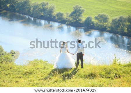 Bride and groom look at the river