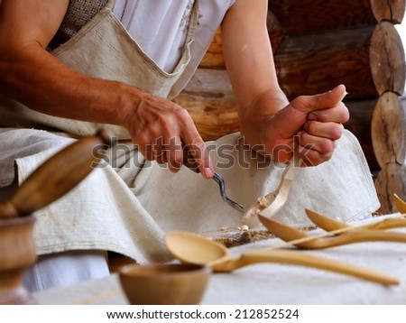 Hands of the craftsman carve a wooden spoon a gouge.