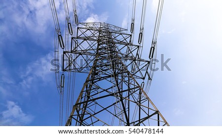 Electricity pylon silhouetted against blue sky sunshine background. High voltage tower