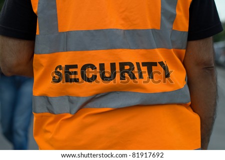 Back of a security guard in orange uniform jacket
