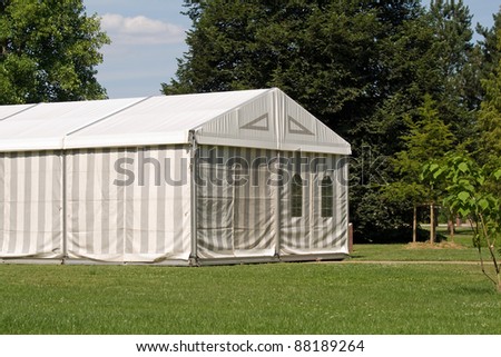 A white party or event tent on a meadow in a public park