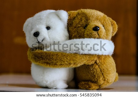 White and brown teddy bears hugging.