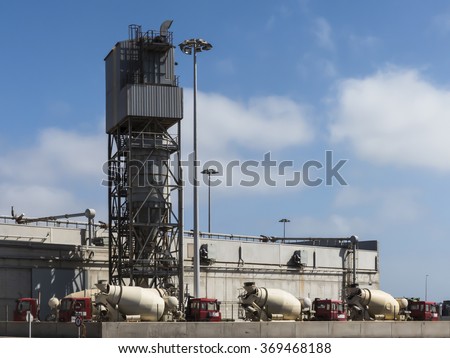 Cement factory with trucks in line waiting to load cement, construction material for delivery.